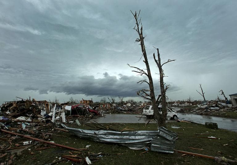 Storm clouds build in the distance as in Moore residents clean up after Monday&#039;s tornado. (Charlie Riedel/ AP)