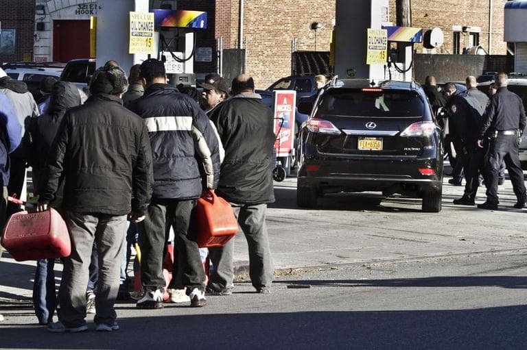 Police direct cars to pumps while people stand in line with containers for gas in the wake of Superstorm Sandy, on Friday, Nov. 9, 2012 in the Brooklyn borough of New York. Police were at gas stations to enforce a new gasoline rationing plan that lets motorists fill up every other day. (AP)
