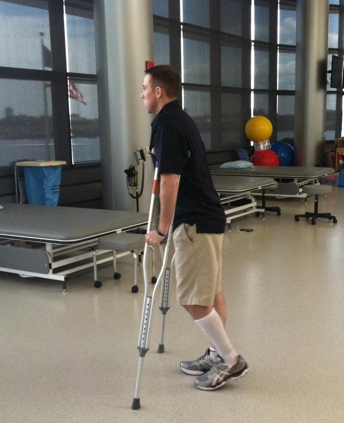 Richard Donohue walks on crutches at Spaulding Rehabilitation Hospital. (Andrea Shea/WBUR)