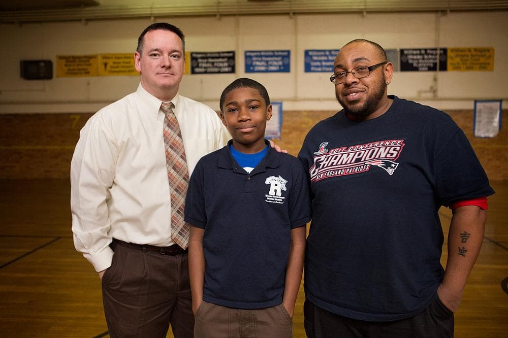 Rogers Middle School football coaches Steve Cahill, left, and Kassim Shavis, right, with eighth grade football player Tyrese Myers. (Jesse Costa/WBUR)