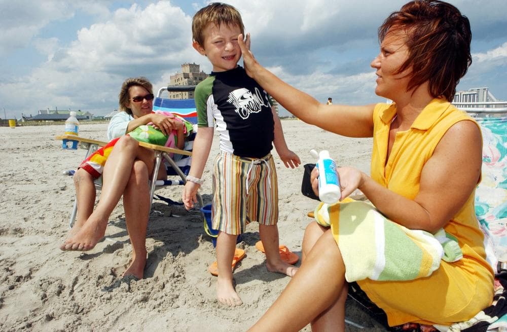 Bernadine Boyce, of Allentown, Pa., applies sunscreen to Bruno Barber, 5, of Atlantic City, as mom, Natalia Barber, watches in Atlantic City, N.J., in June 2006. (Mary Godleski/AP)