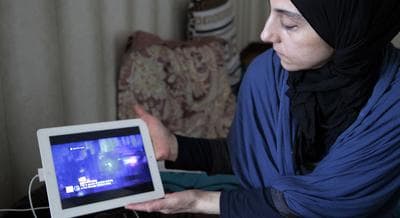 Zubeidat Tsarnaeva, mother of the two Boston bombing suspects, shows videos on an iPad she says show her sons could not have been involved in last month's Boston Marathon bombings. Authorities accuse Tamerlan Tsarnaev, who was slain in a shootout with police, and his younger brother Dzhokhar of organizing the attacks, which killed three. (Musa Sadulayev/AP)