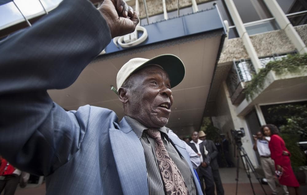 An elderly Mau Mau veteran raises his fist in the air to celebrate as he leaves a press conference announcing a settlement in their legal case for compensation against the British Government, in Nairobi, Kenya Thursday, June 6, 2013. (Ben Curtis/AP)