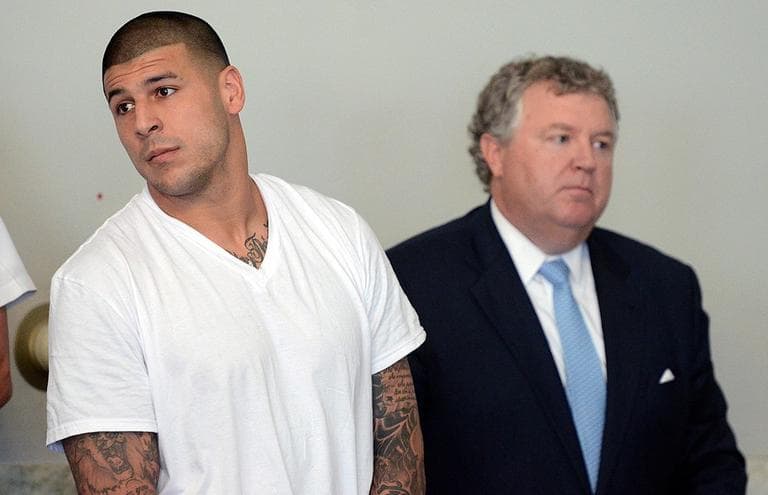 Former New England Patriots tight end Aaron Hernandez, left, stands with his attorney Michael Fee, right, during arraignment in Attleboro District Court Wednesday, June 26, in Attleboro, Mass. (Mike George/The Sun Chronicle via AP)