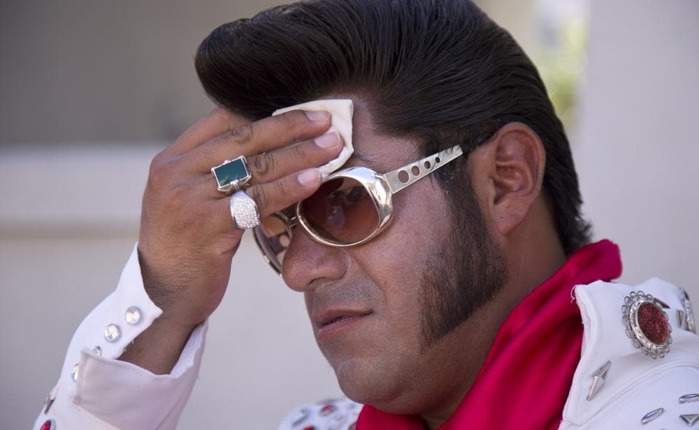 Elvis impersonator Cristian Morales wipes sweat from his brow while standing out on The Strip posing for photos with tourists, Thursday, June 27, 2013 in Las Vegas. (Julie Jacobson/AP)