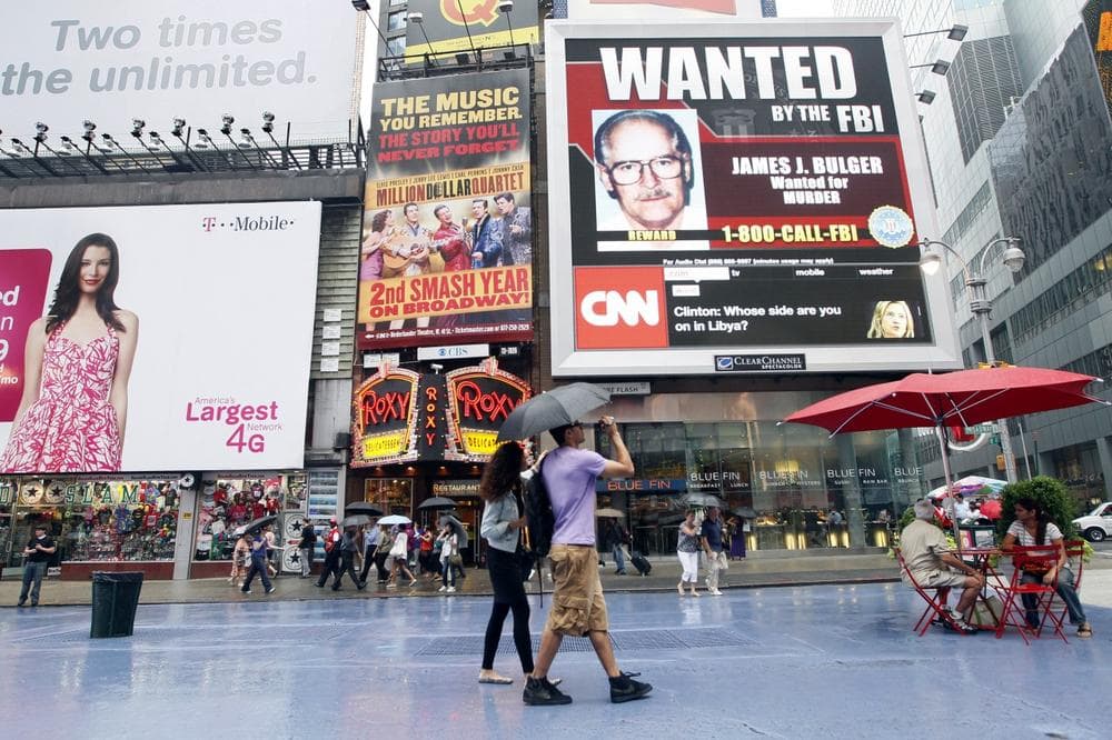 A couple walks past an FBI video looking for mob boss James &quot;Whitey&quot; Bulger on display in New York's Times Square, Thursday, June 23, 2011. After an international manhunt, the FBI finally caught the 81-year-old Bulger at an apartment in Santa Monica along with longtime girlfriend Catherine Greig on Wednesday, just days after the government launched a publicity campaign to locate the fugitive crime boss by circulating pictures of Greig on daytime TV and on billboards, the FBI said. (AP)