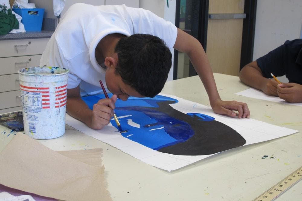A student paints at Orchard Gardens School. (Ava Aguado/WBUR)