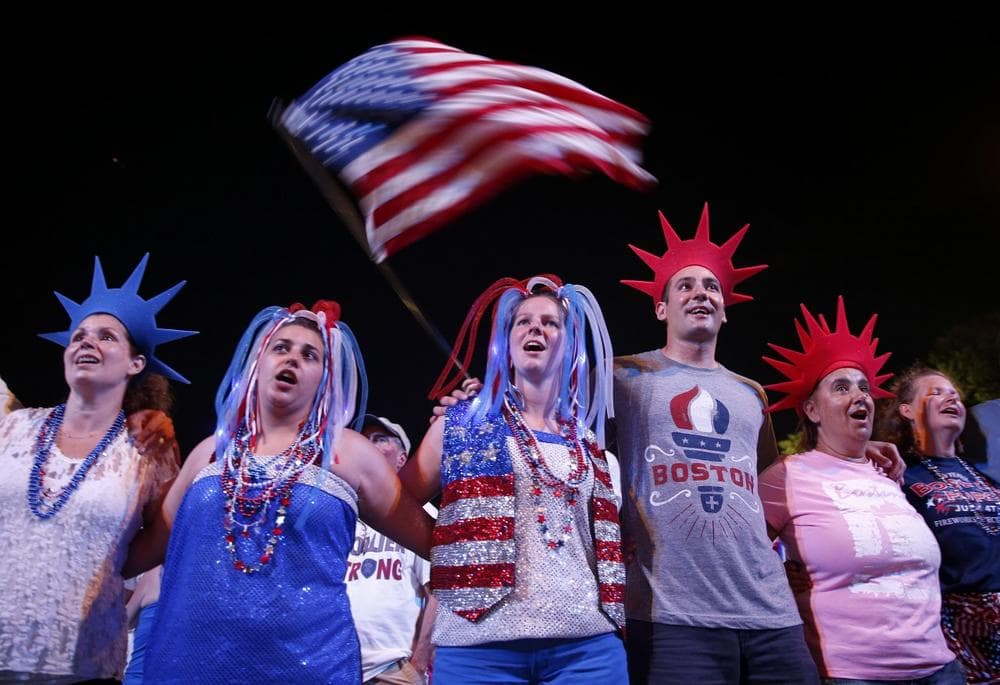 Audience members join arms as the Boston Pops play God Bless America during their Fourth of July Concert at the Hatch Shell in Boston, Thursday, July 4, 2013. (Michael Dwyer/AP)