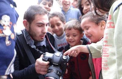 Syrian citizen journalist Fidaa al-Baali is pictured with his camera and a group of children. (Activists News Association/Facebook)