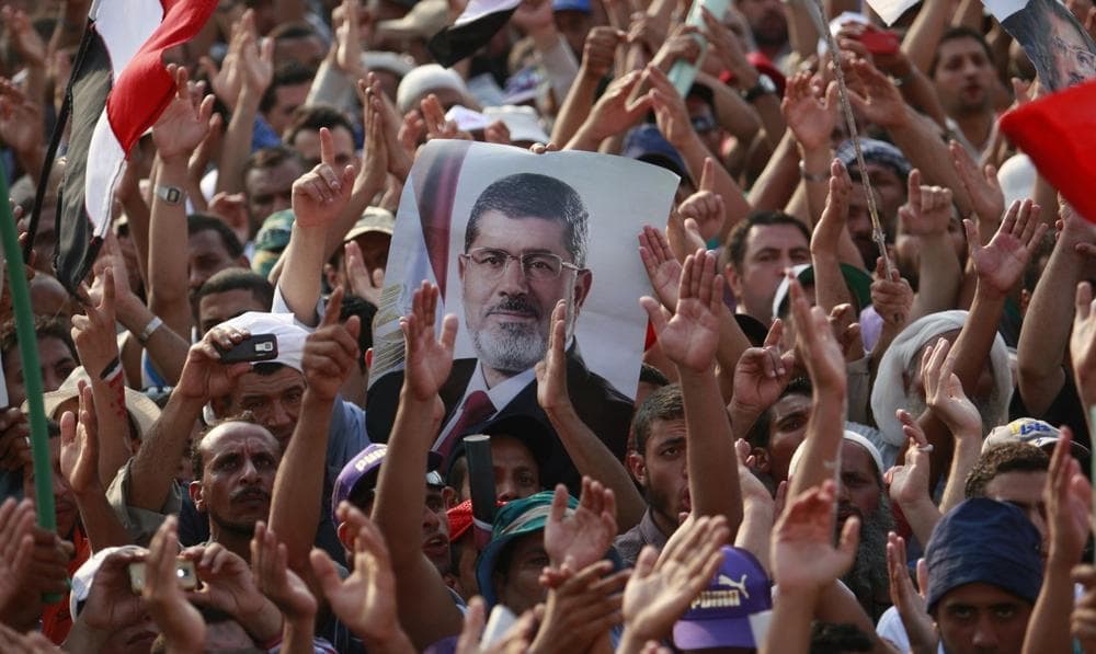 Supporters of ousted President Mohammed Morsi, seen in poster, protest in Nasr City, Cairo, Egypt, Tuesday, July 9, 2013. (Nasser Shiyoukhi/AP)