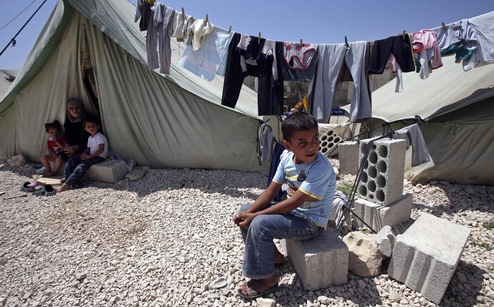 A Syrian refugee boy, right, sits outside his tent next to his family at a temporary refugee camp in the eastern Lebanese town of Marj near the border with Syria, Lebanon, Monday, May 20, 2013. (Hussein Malla/AP)