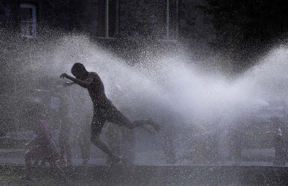 Kids cool off in the spray of an open hydrant on a hot evening in Lawrence, Mass. Tuesday, July 16, 2013. (Elise Amendola/AP)