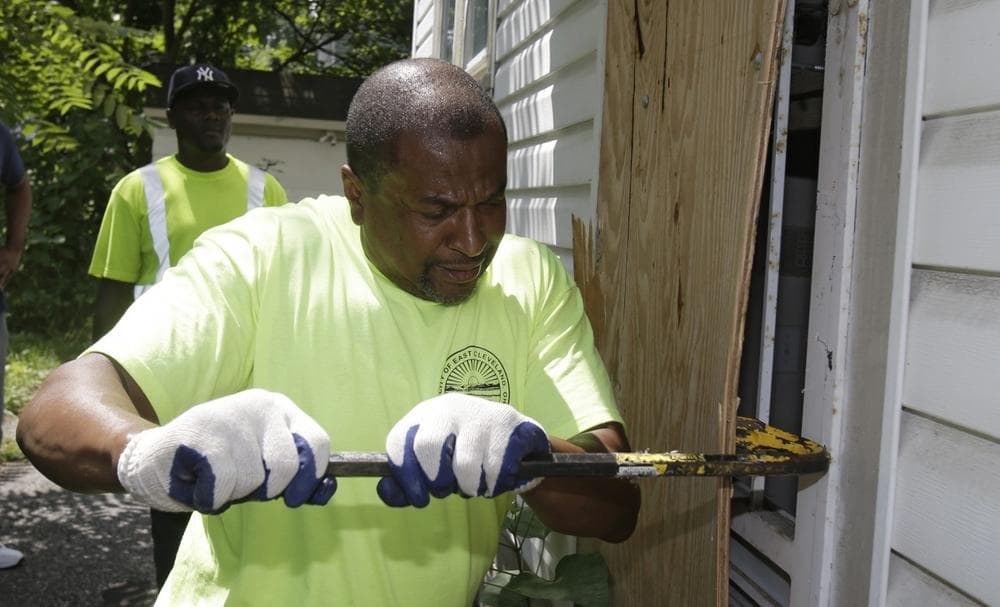 City of East Cleveland service department employee Ray Allen breaks into an abandoned house so searchers can enter Sunday, July 21, 2013, in East Cleveland, Ohio. The police chief told volunteers to check vacant houses in a neighborhood where three bodies were found wrapped in plastic bags. (Tony Dejak/AP)