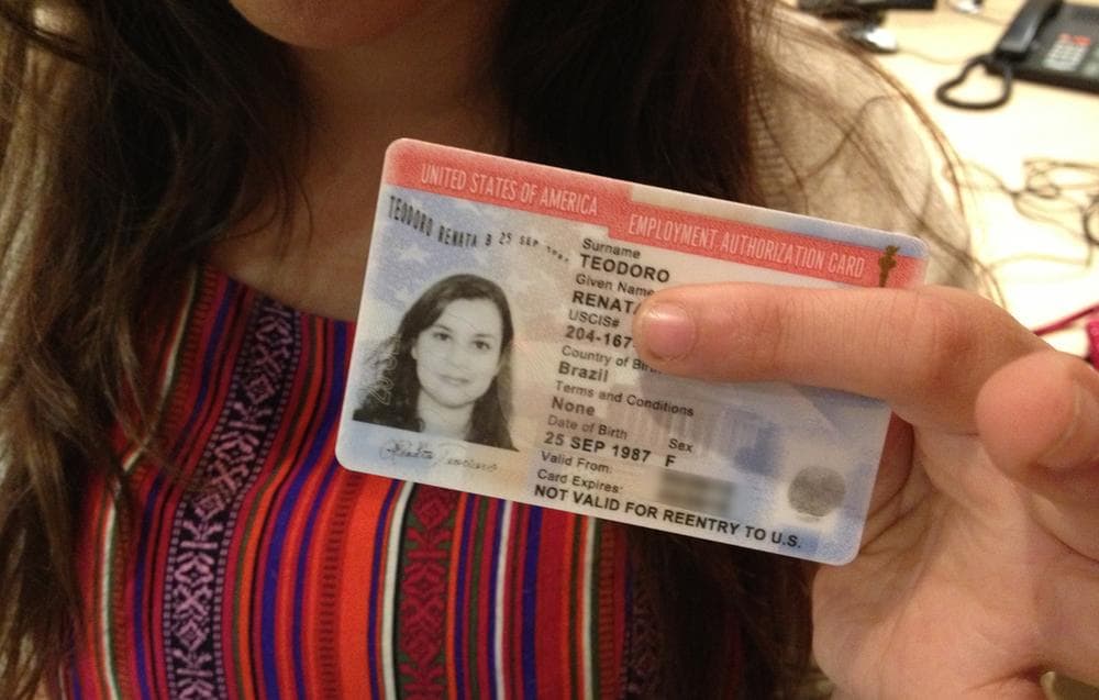 Renata Teodoro holds up her U.S. employment authorization card. (Here &amp; Now)