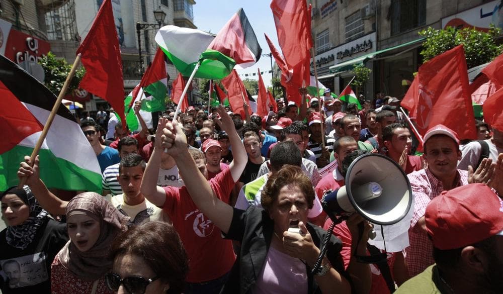 Palestinians wave national and PFLP (Popular Front for the Liberation of Palestine) flags in the West Bank city of Ramallah, during a protest against resuming peace talks with Israel, Sunday, July 28, 2013. (Majdi Mohammed/AP)