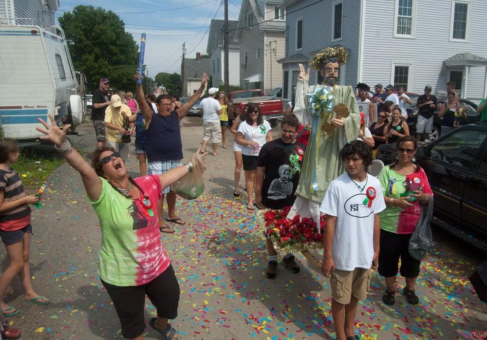 Three years ago Robyn McNair (left) and her sister Amy Clayton (in matching shirt at right) began holding a mini, tribute reenactment of the St. Peter’s Fiesta during the festival weekend. McNair shouts blessings as her son Noah McNair (in black shirt) and nephew Jacob Belcher carry their replica St. Peter statue down Orchard Street. (Greg Cook)
