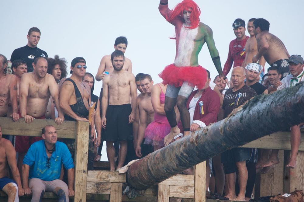 A Greasy Pole walker, costumed in the Italian colors, attempts to cross the slippery pole.