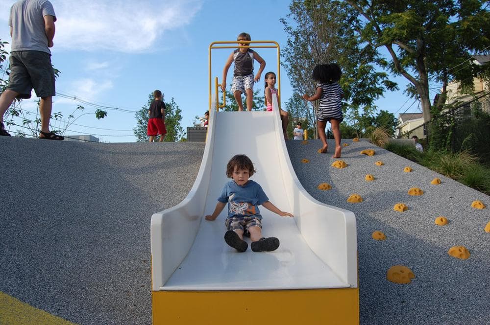 After sliding down, children can climb back up using the grips built into the hill at right. (Greg Cook)