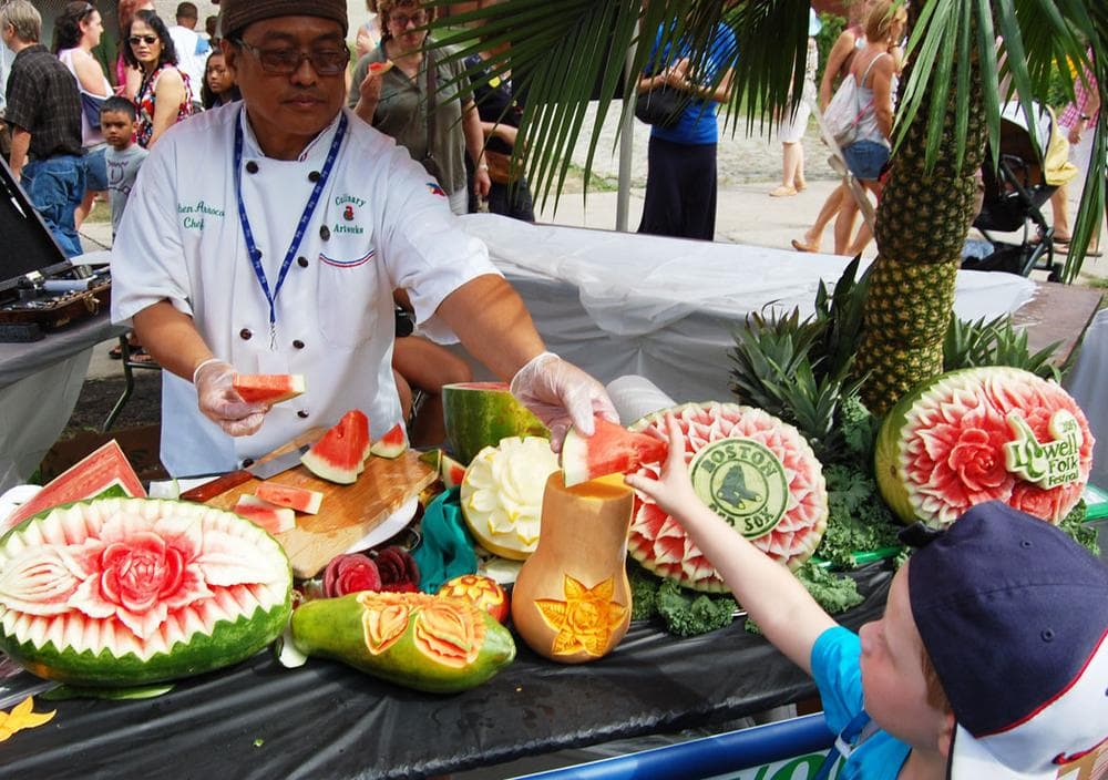 Ruben Arroco of Lowell, who carves watermelon into fabulous floral designs, hands out fruit. (Greg Cook)