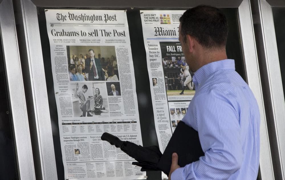 A visitor views the front page of the Washington Post, displayed outside the Newseum in Washington, Tuesday, Aug. 6, 2013, a day after it was announced that Amazon.com founder Jeff Bezos bought the Washington Post for $250 million. (Evan Vucci/AP)