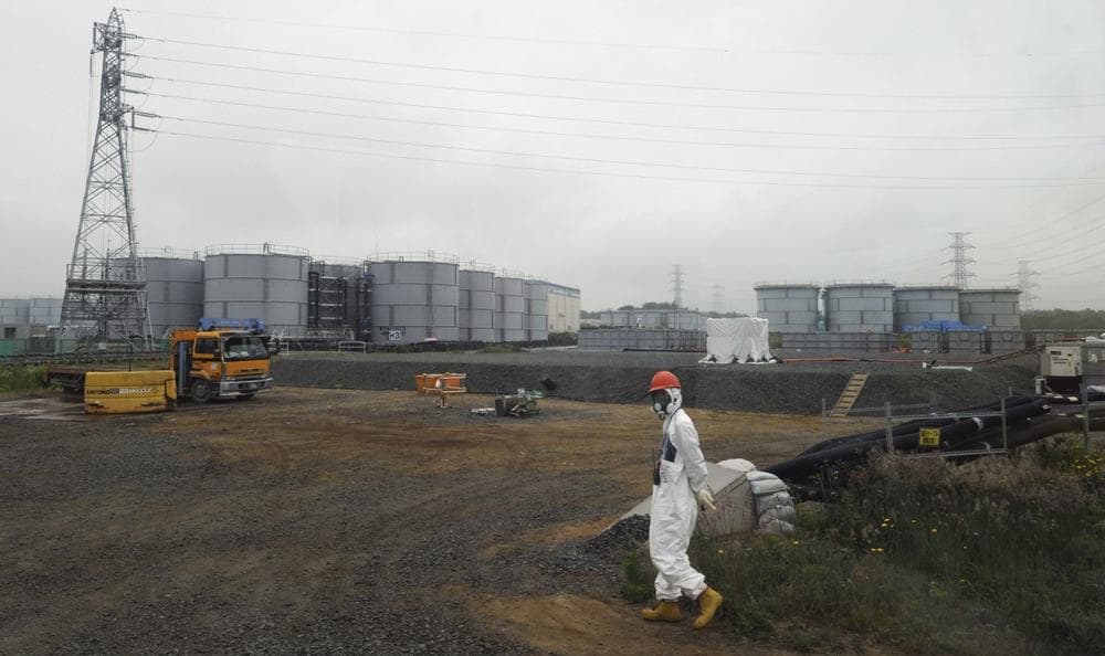 A construction worker walks beside the underground water tank and water tanks at the Fukushima Dai-ichi nuclear plant at Okuma in Fukushima prefecture, Japan, June 12, 2013. (Toshifumi Kitamura/AP)