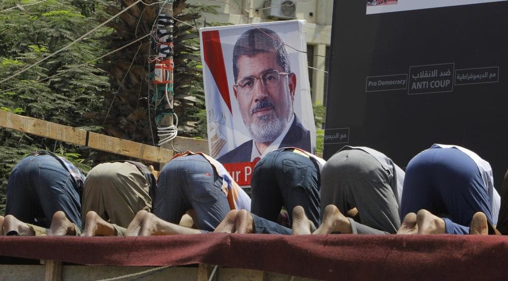 Supporters of Egypt&#039;s ousted President Mohammed Morsi pray in front of his poster in Nahda Square, where protesters have installed their camp near Cairo University in Giza, southwestern Cairo, Egypt, Monday, Aug. 12, 2013. (Amr Nabil/AP)