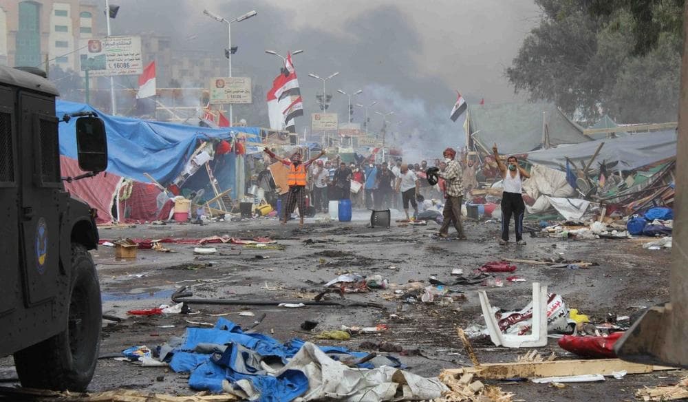 Supporters of ousted Islamist President Mohammed Morsi, stand among debris and smoke in background as they confront Egyptian security forces trying to clear the smaller of the two sit-ins, near the Cairo University campus in Giza, Cairo, Egypt, Wednesday, Aug. 14, 2013. (Imad Abdul Rahman/AP)