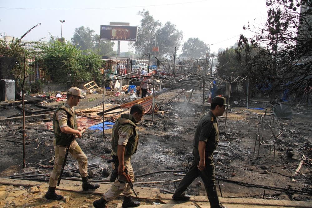 Members of the Egyptians Army walk among the smoldering remains of the largest protest camp of supporters of ousted President Mohammed Morsi, that was cleared by security forces, in the district of Nasr city, Cairo, Egypt. (Ahmed Gomaa/AP)