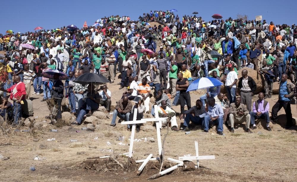 Mine workers sit on a hill where a year ago, police opened fire on fellow workers killing 34 and injuring 78, during a memorial service near the Marikana, South Africa, platinum mine, Friday Aug. 16, 2013. (Themba Hadebe/AP)