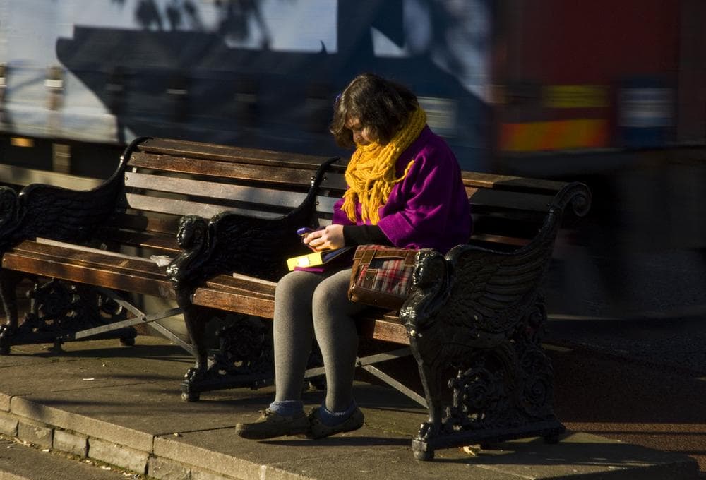 A girl texts on a bench. (James Offer/Flickr)