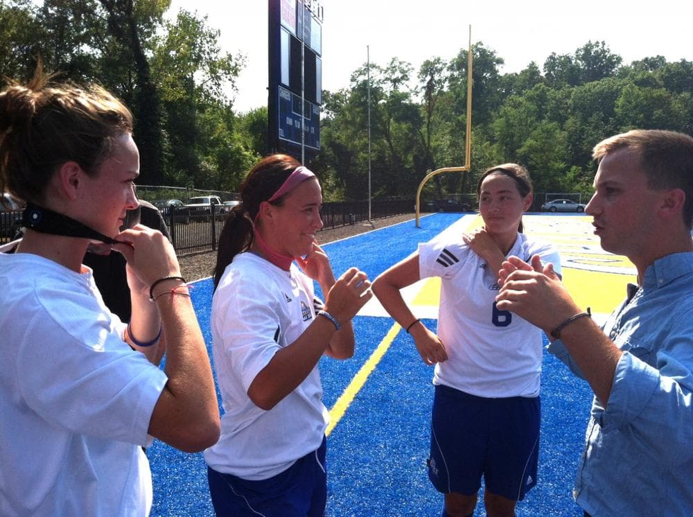 Members of the University of New Haven women's soccer team are shown how to wear the head sensors. (Harriet Jones/WNPR)