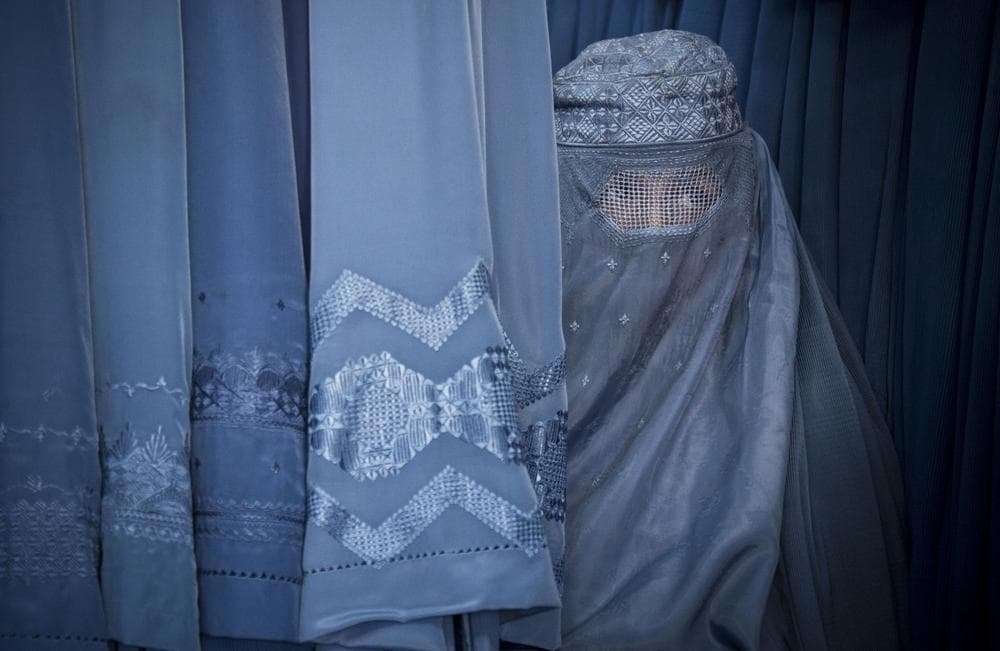 An Afghan woman peers through the the eye slit of her burqa as she waits to try on a new burqa in shop in the old town of Kabul, Afghanistan, April 11, 2013. (Anja Niedringhaus/AP)