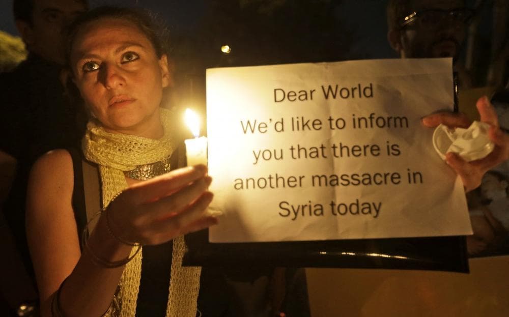 A Syrian woman who lives in Beirut holds a candle and placard during a vigil against the alleged chemical weapons attack on the suburbs of Damascus, in front the United Nations headquarters in Beirut, Lebanon, Wednesday, Aug. 21, 2013. (Hussein Malla/AP)