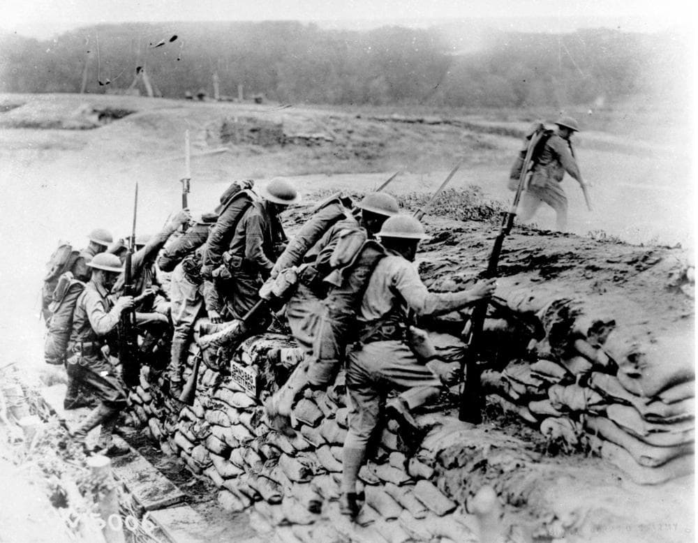 American troops carrying guns climb over a sandbag revetment in France during World War I in 1918. (AP Photo)