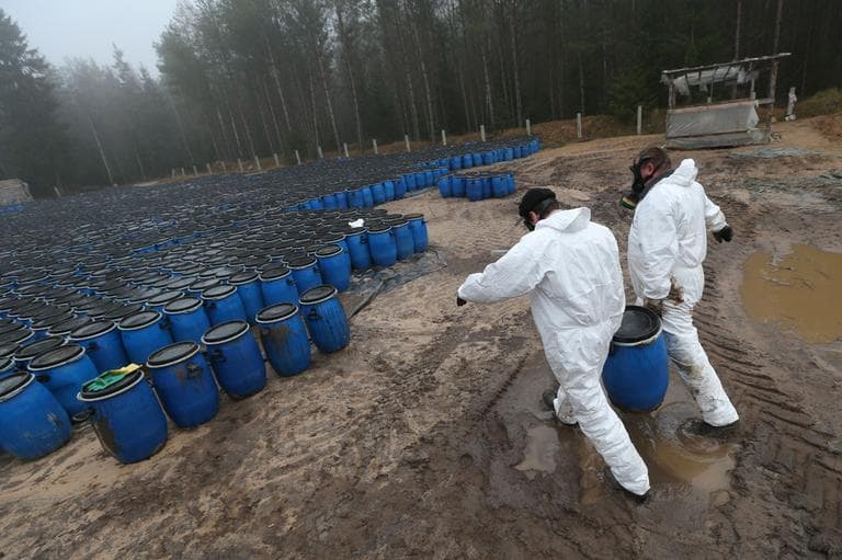 Belarusian Emergency Ministry employees carry plastic barrel with pesticide at a burial site in a forest near the village of Novaya Strazha, some 200 kms (125 miles) southwest of Minsk, Wednesday, Nov. 14, 2012. (AP)