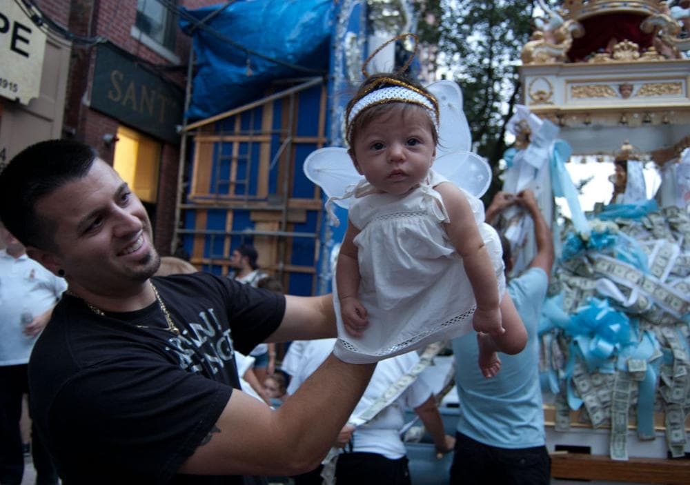 Three-month-old Antonia Graziano, dressed as an angel, is held up by her father Dave. (Greg Cook/WBUR)