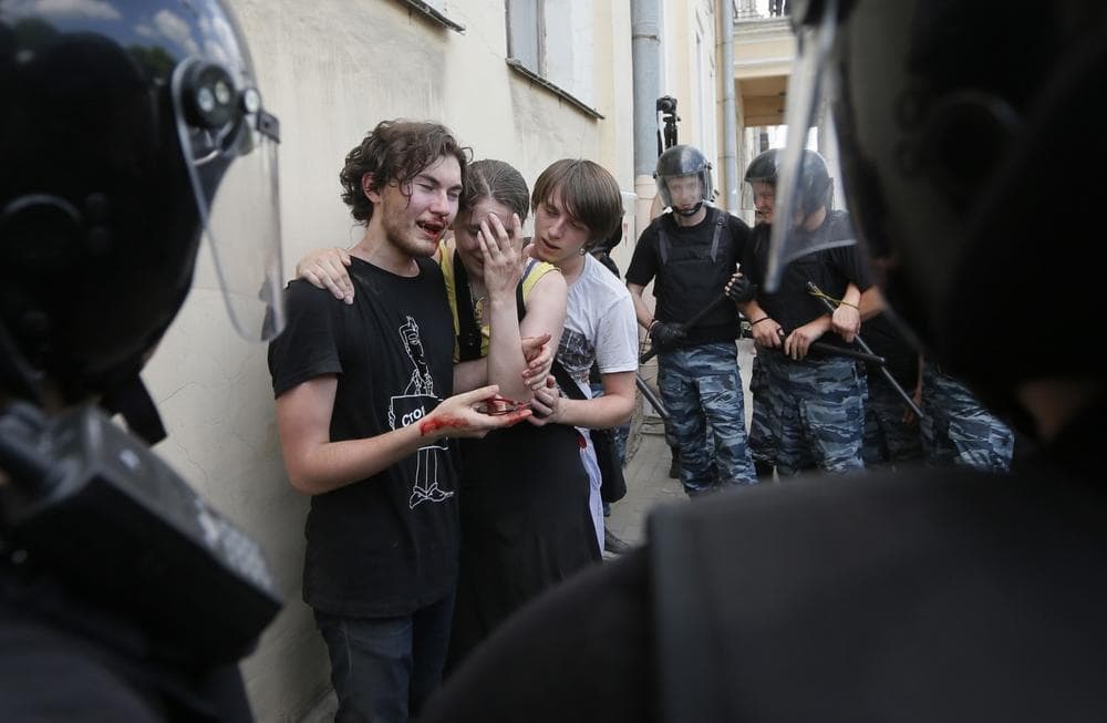 Riot police guard gay rights activists who were beaten by anti-gay protesters during an authorized gay rights rally in St. Petersburg, Russia, June 29, 2013. (Dmitry Lovetsky/AP)