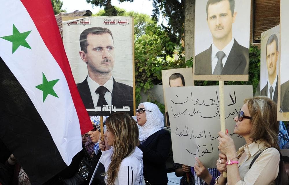 In this photo released by the Syrian official news agency SANA, Syrian, Iraqi, and Palestinian women hold portraits of Syrian President Bashar Assad during a demonstration against the United States considering launching a punitive strike against the Syrian regime, in front of the UN headquarters in Damascus, Syria, Wednesday, Sept. 4, 2013. (SANA via AP)