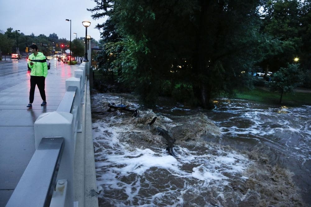 A man walks past dangerously high Boulder Creek following overnight flash flooding in downtown Boulder, Colo., Thursday, Sept 12, 2013. (Brennan Linsley/AP)