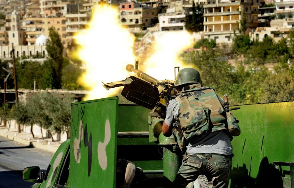 In this Saturday, Sept. 7, 2013 photo released by the Syrian official news agency SANA, a Syrian military solider fires a heavy machine gun during clashes with rebels in Maaloula village, northeast of the capital Damascus, Syria. (SANA via AP)