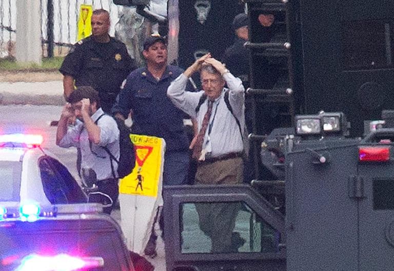 People hold their hands to their heads as they are escorted out of the building where a deadly shooting rampage occurred at the Washington Navy Yard Monday. (Jacquelyn Martin/AP)