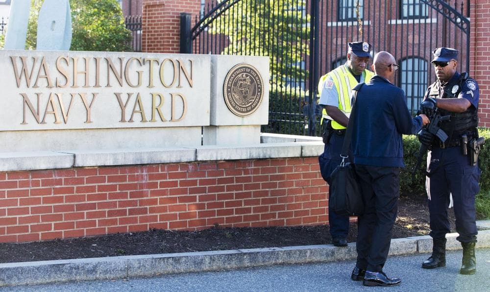 An officer who said he works for the Department of Defense, right, checks an ID outside of the closed Washington Navy Yard in Washington, D.C., on Tuesday, Sept. 17, 2013, the day after a gunman launched an attack there. (Jacquelyn Martin/AP)
