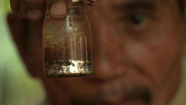 A gold miner in Indonesia holds up a bottle of mercury. (BBC)