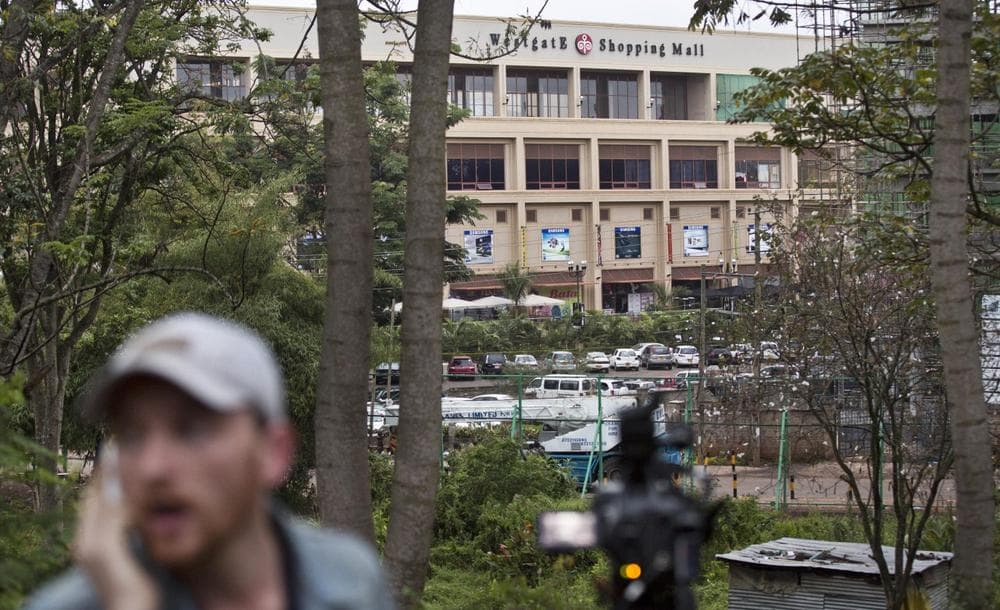 A television reporter makes a telephone call while filming during a bout of heavy gunfire shortly after dawn, at the Westgate Mall in Nairobi, Kenya Tuesday, Sept. 24, 2013. (Ben Curtis/AP)