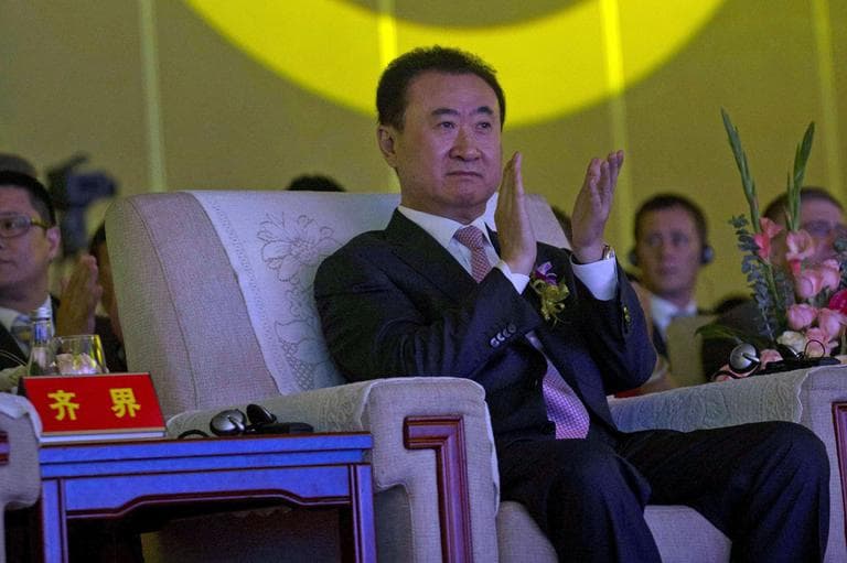 In this Wednesday, June 19, 2013, file photo, Wanda Chairman Wang Jianlin applauds in front of the logo for Dalian Wanda Group during an event at a hotel in Beijing, China. (AP)
