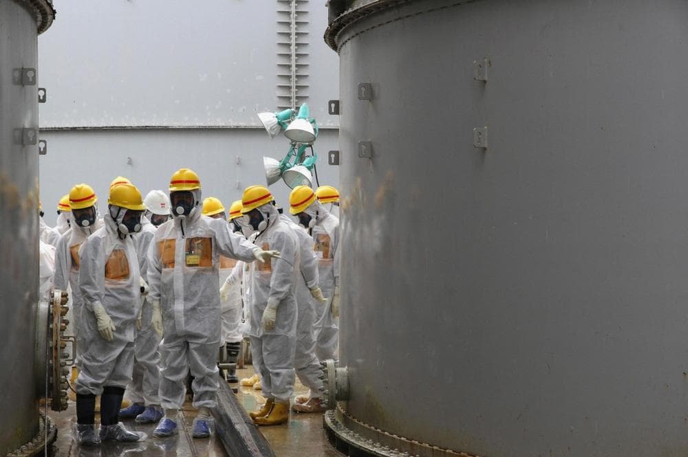 In this photo provided by Nuclear Regulation Authority (NRA), NRA commissioners inspect storage tanks used to contain radioactive water at the Fukushima Dai-ichi nuclear power plant, operated by Tokyo Electric Power Co. (TEPCO), in Okuma in Fukushima prefecture, northern Japan, Friday, Aug. 23, 2013. (AP/Nuclear Regulation Authority)