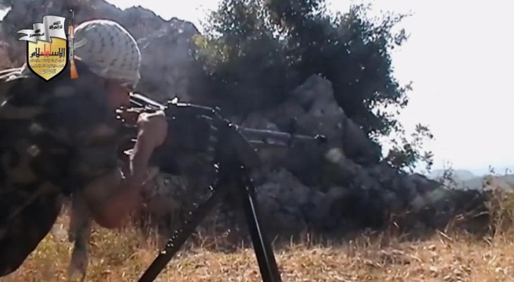 In this image taken from Sunday, Aug. 11, 2013, video obtained from the Sham News Network, which has been authenticated based on its contents and other AP reporting, a rebel fighter fires a gun in a valley in an unidentified location in Latakia province, Syria. (Sham News Network via AP video)