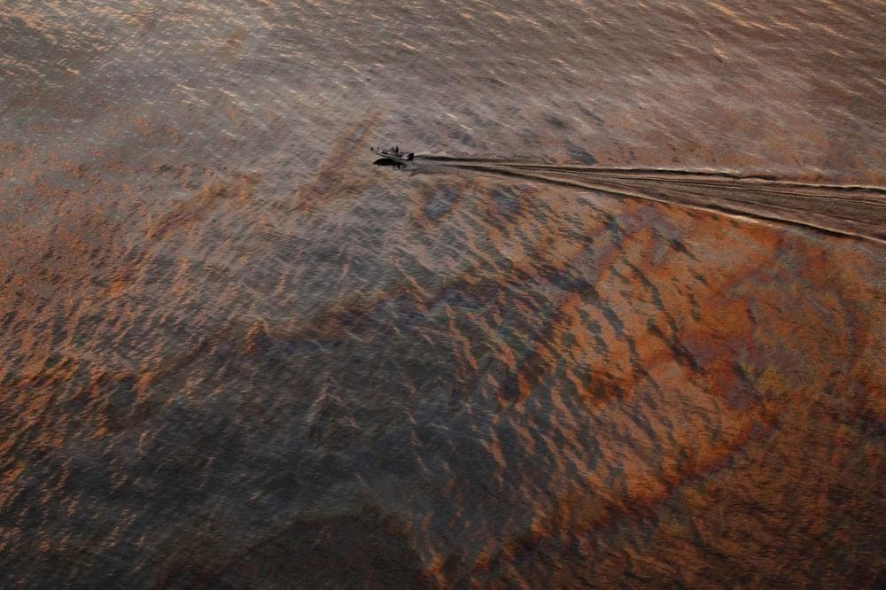 In this July 31, 2010 file photo, a boat motors through oil sheen from the Deepwater Horizon oil spill off East Grand Terre Island, where the Gulf of Mexico meets Barataria Bay, on the Louisiana coast, at sunset on. (AP/Gerald Herbert)