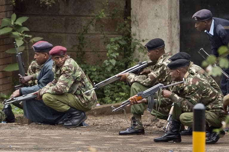 Armed police from the General Service Unit take cover behind a wall during a bout of gunfire, outside the Westgate Mall in Nairobi, Kenya Monday, Sept. 23, 2013. (AP)