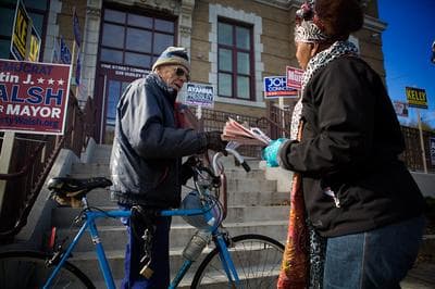 Lenor Johnson hands out leaflet to voters in front of Vine Street Community Center in Roxbury. (Jesse Costa/WBUR)